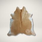 Natural beige cowhide rug with soft neutral tones and an organic freeform shape.