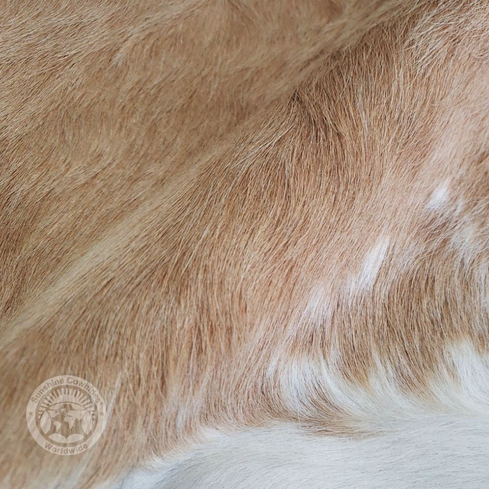 Natural beige cowhide rug with soft neutral tones and an organic freeform shape.