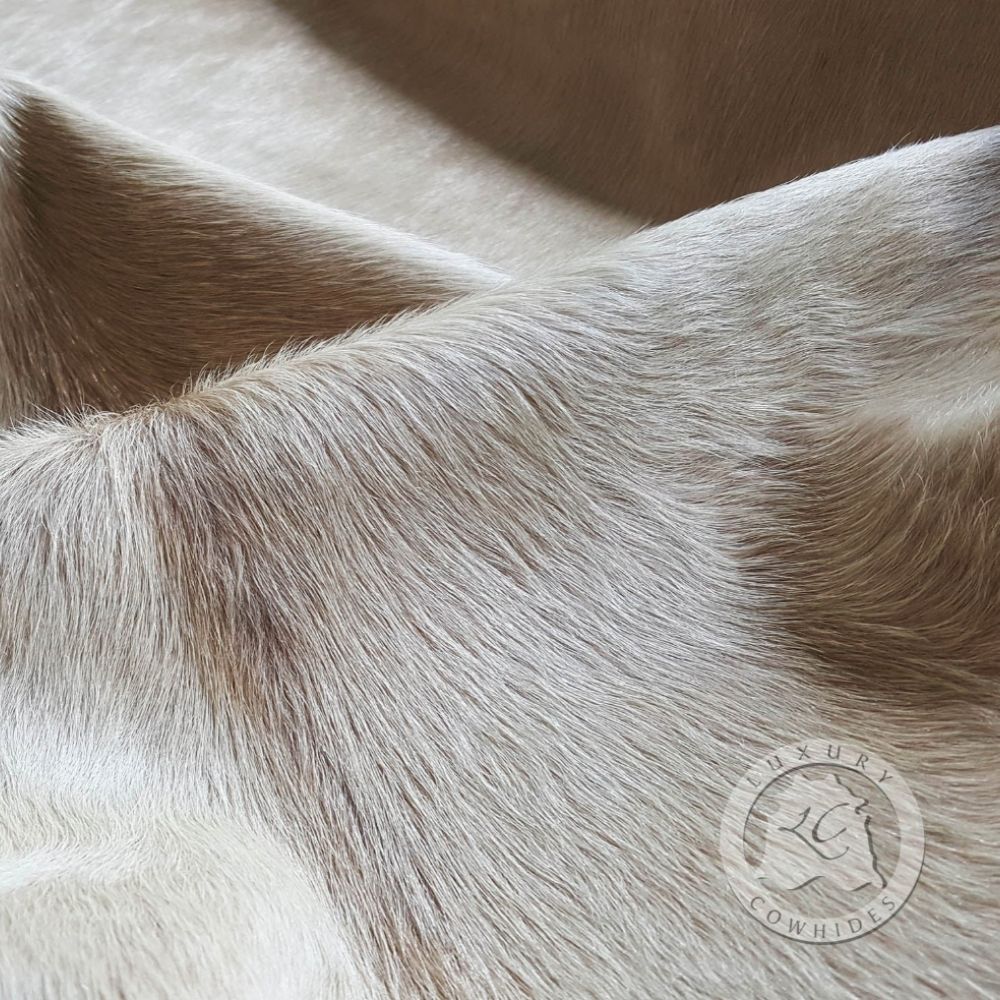 Natural champagne cowhide rug with soft neutral sheen and organic shape.