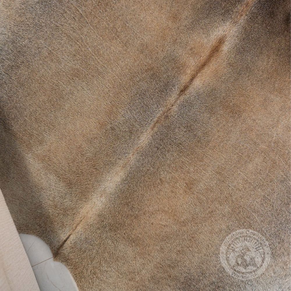 Natural grey-beige cowhide rug featuring soft neutral tones and organic shape.