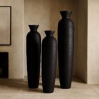 Set of three tall black sculptural vases with matte finish and flared openings in graduated sizes.