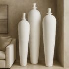 Set of three tall white sculptural vases with smooth matte finish and modern elongated silhouettes.