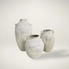 Set of three large handcrafted vases with a distressed, textured white finish and classic Mediterranean-inspired shapes.