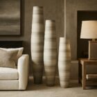Set of three tall sculptural vases in soft grey and ivory tones with a smooth gradient finish and elongated cylindrical shapes.