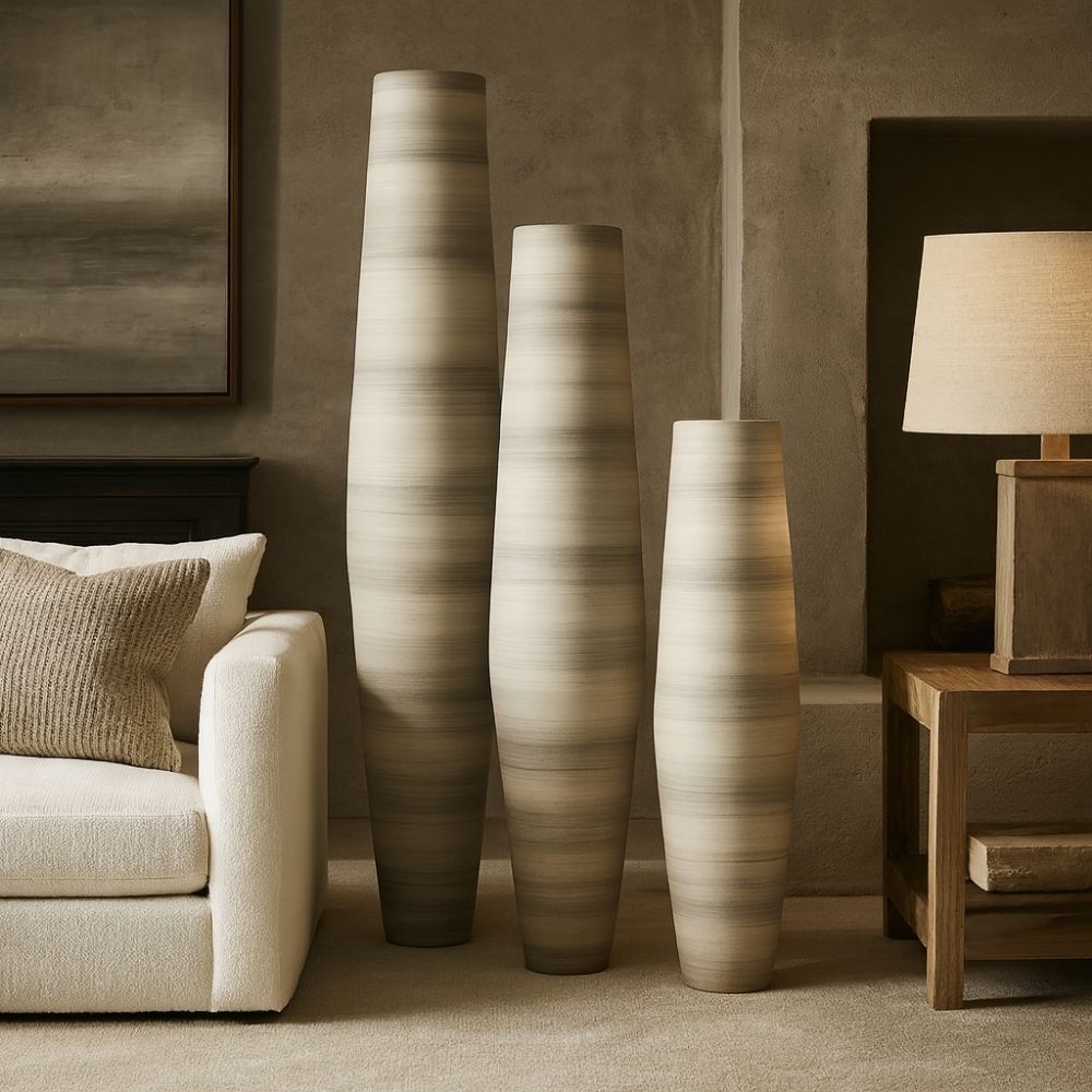 Set of three tall sculptural vases in soft grey and ivory tones with a smooth gradient finish and elongated cylindrical shapes.