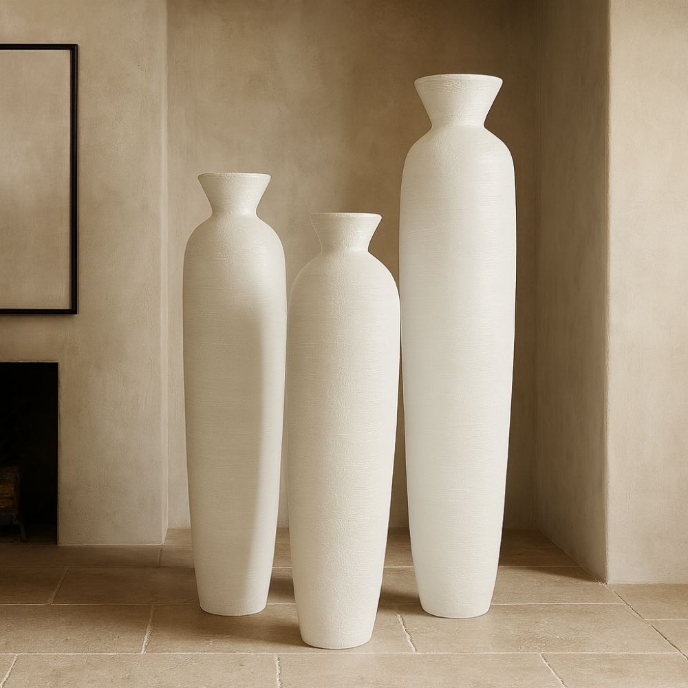Set of three tall white sculptural vases with a hand-textured matte finish and flared openings in graduated sizes.