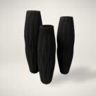 Set of three tall matte black vases with organic carved texture and sculptural, elongated silhouettes.