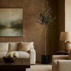 Artificial olive branch tree with slender trunk and lush green leaves in a black pot.