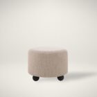Round beige pouf with textured upholstery and rounded black feet.