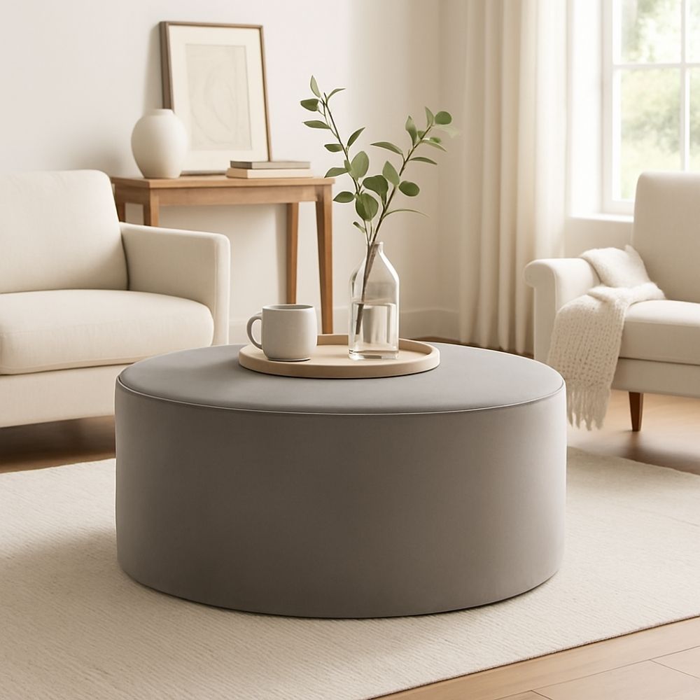 Universal Kirkos round ottoman in soft grey fabric upholstery