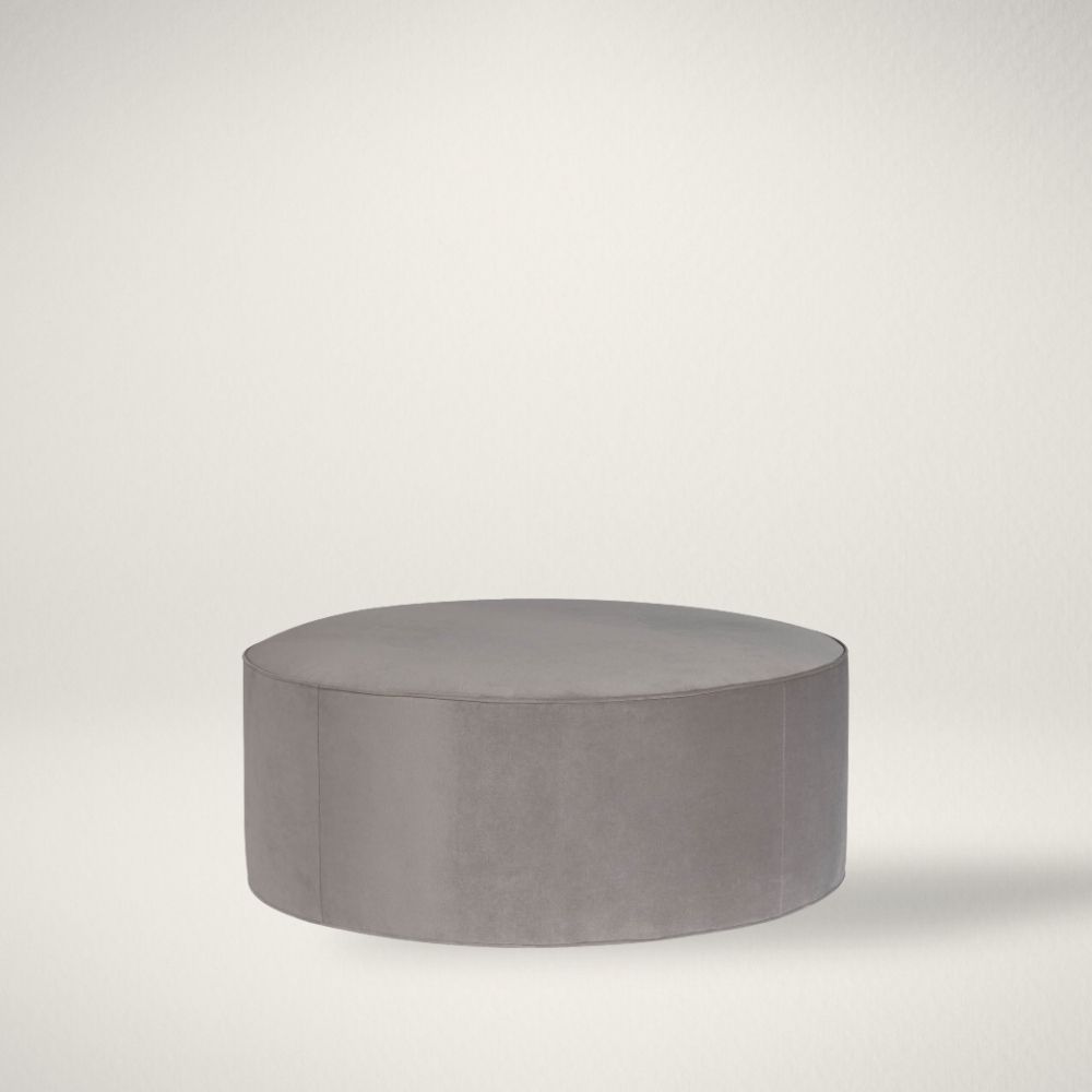UN KIRKOS Universal Kirkos round ottoman in soft grey fabric upholstery