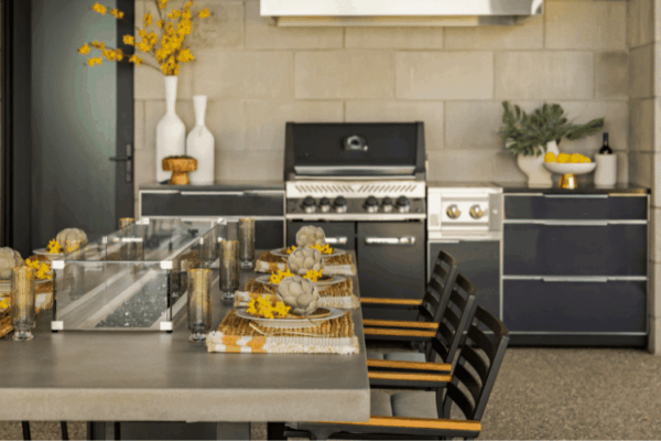 Luxury outdoor kitchen with grill and dining table at lakefront home designed by Urbanhome Interior Design