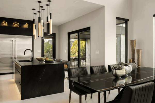 Modern dining room with black stone table beside contemporary kitchen island in the Modern Manor home designed by Urbanhome Interior Design