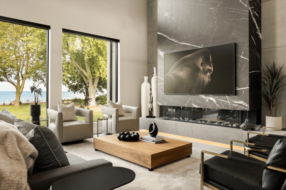 Modern living room with marble fireplace feature wall and lakefront views in The Modern Manor designed by Urbanhome Interior Design