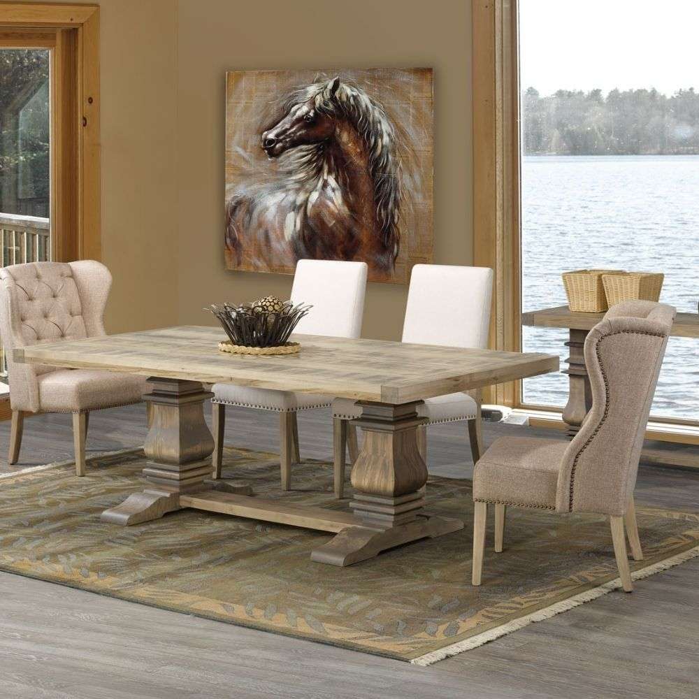 Rectangular wood dining table with a thick top, carved pedestal legs, and a horizontal stretcher base in a soft grey-brown finish.
