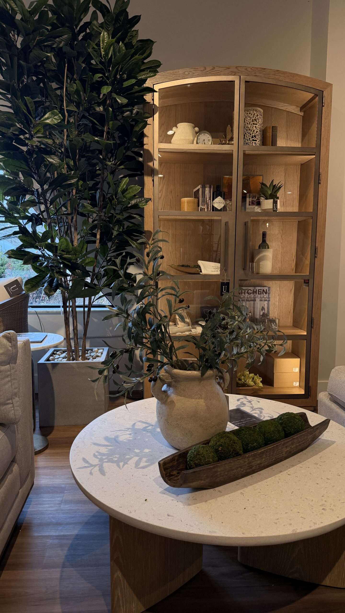 Organic modern living room furniture display featuring a curved oak coffee table, arched wood cabinet, and luxury home décor styled by Urbanhome Interior Design for upscale homes in Windsor-Essex and Chatham-Kent.