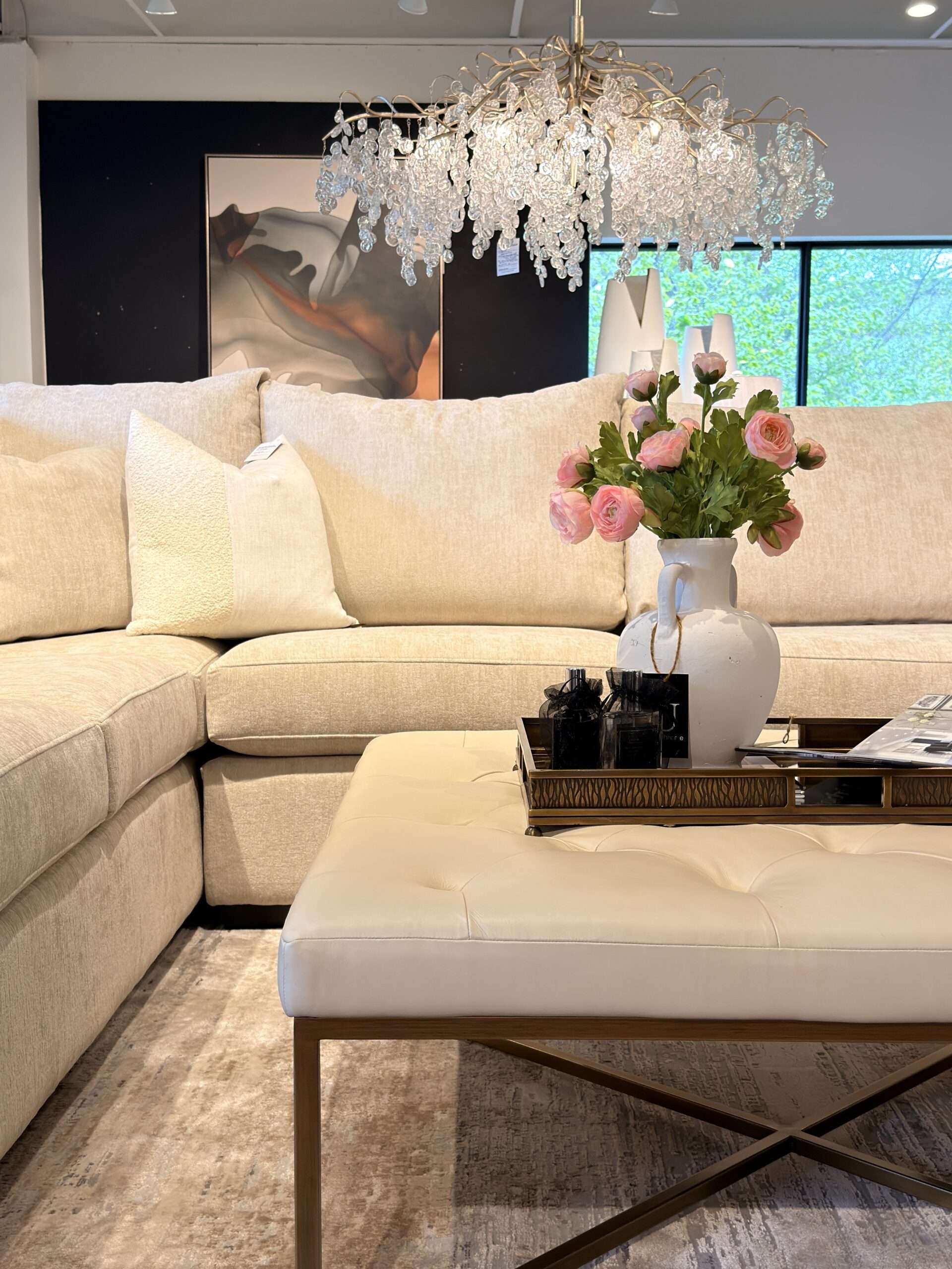 Luxury cream sectional sofa beneath a statement chandelier in a high-end furniture showroom in Windsor Ontario.
