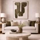 Abstract wall art featuring bold organic shapes in deep green tones on a soft neutral background, framed in a light wood frame.