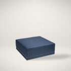 Square upholstered ottoman in a deep blue textured fabric with nailhead trim detailing along the base.