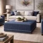 Square upholstered ottoman in a deep blue textured fabric with nailhead trim detailing along the base.