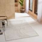 Cream textured area rug with raised geometric patterns and subtle fringe detailing along the edges.