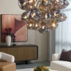 Modern chandelier with brass frame and clustered smoked glass globe shades creating a sculptural lighting fixture.