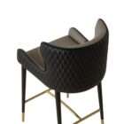 Modern counter stool with taupe upholstered seat, black quilted back detail, and black metal legs with brass accents.