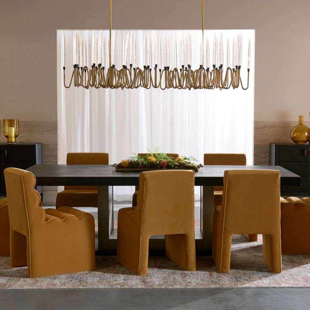 Modern linear chandelier with brass frame and multiple candle-style lights arranged in a sculptural wave pattern.