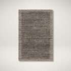 Textured area rug in layered grey and brown tones with subtle horizontal striations.
