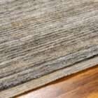 Textured area rug in layered grey and brown tones with subtle horizontal striations.