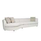 Curved sectional sofa in a soft neutral fabric with a low profile, rounded arms, and plush seating, accented with patterned throw pillows.