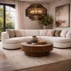 Curved sectional sofa in a soft neutral fabric with a low profile, rounded arms, and plush seating, accented with patterned throw pillows.