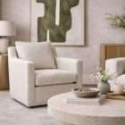 Light neutral upholstered armchair with clean lines, track arms, and a plush seat cushion.