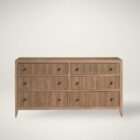 Light wood dresser with six drawers featuring vertical fluted detailing and round metal knobs.