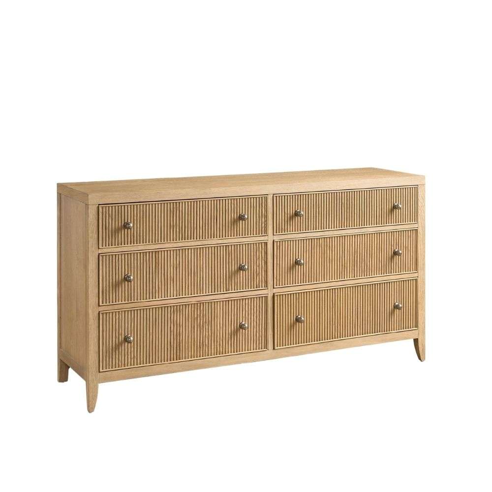 Light wood dresser with six drawers featuring vertical fluted detailing and round metal knobs.