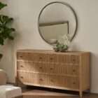 Light wood dresser with six drawers featuring vertical fluted detailing and round metal knobs.
