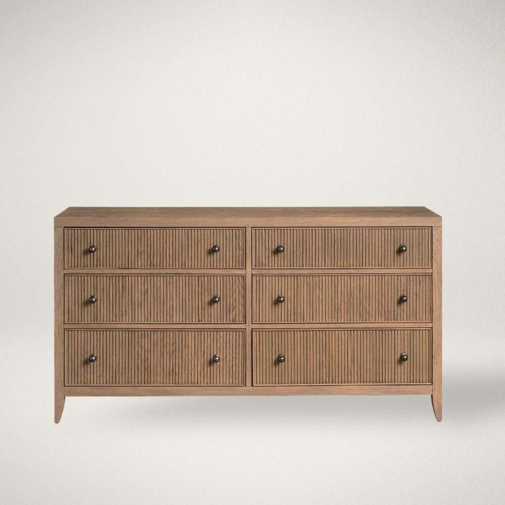 UN CARMEN DRESSER Light wood dresser with six drawers featuring vertical fluted detailing and round metal knobs.