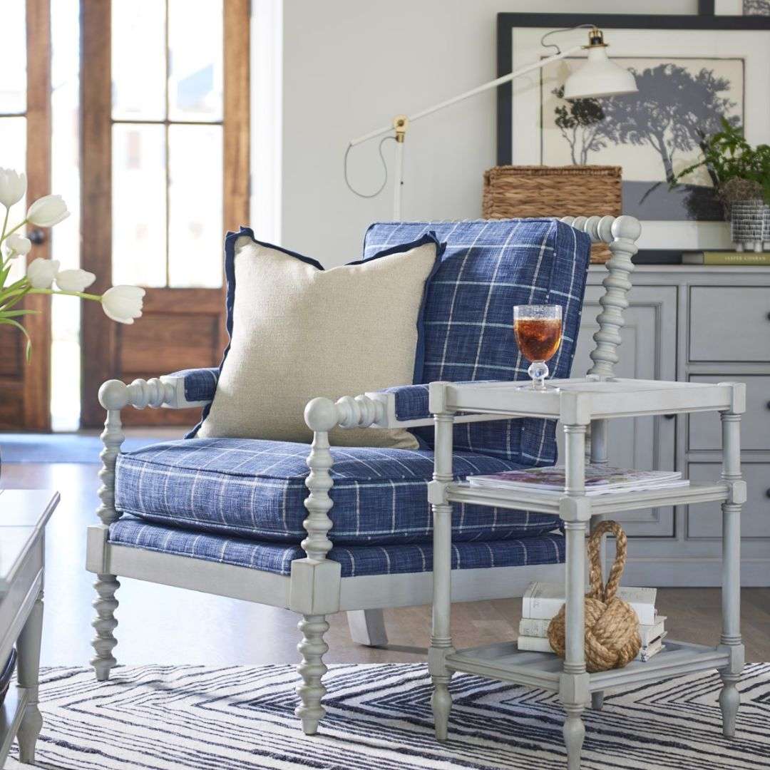 Upholstered accent chair with a natural linen cushion and back, featuring a dark wood frame with turned spindle detailing on the arms and legs.