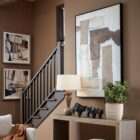 Abstract wall art featuring layered neutral tones with textured beige, cream, and warm brown forms in a black frame.