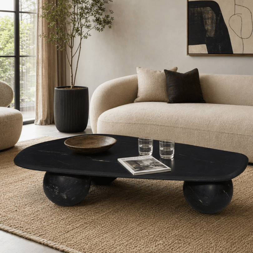Sculptural black marble coffee table paired with a curved cream sofa and natural textured rug.